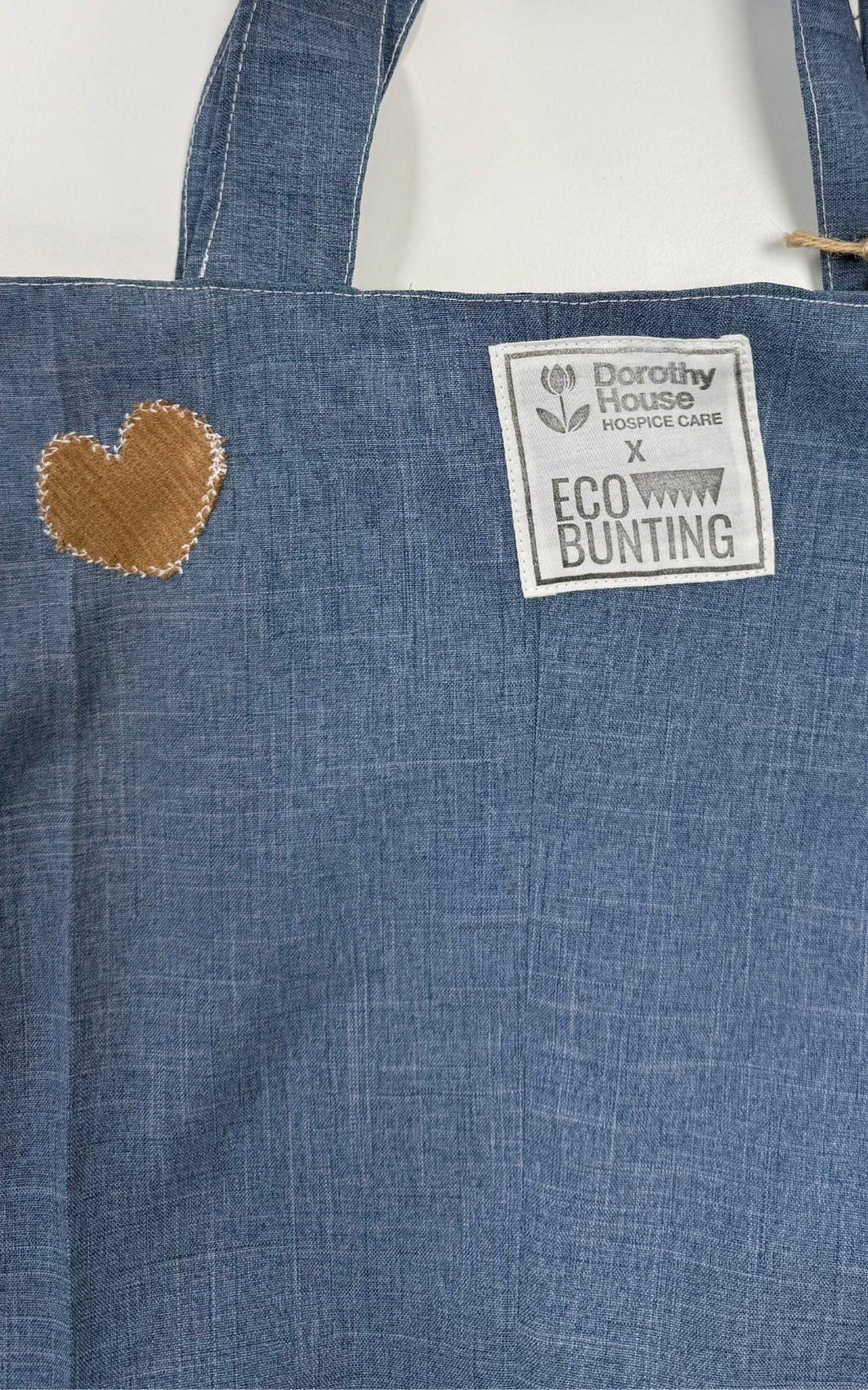 Blue denim apron with a heart patch and a label on a white background