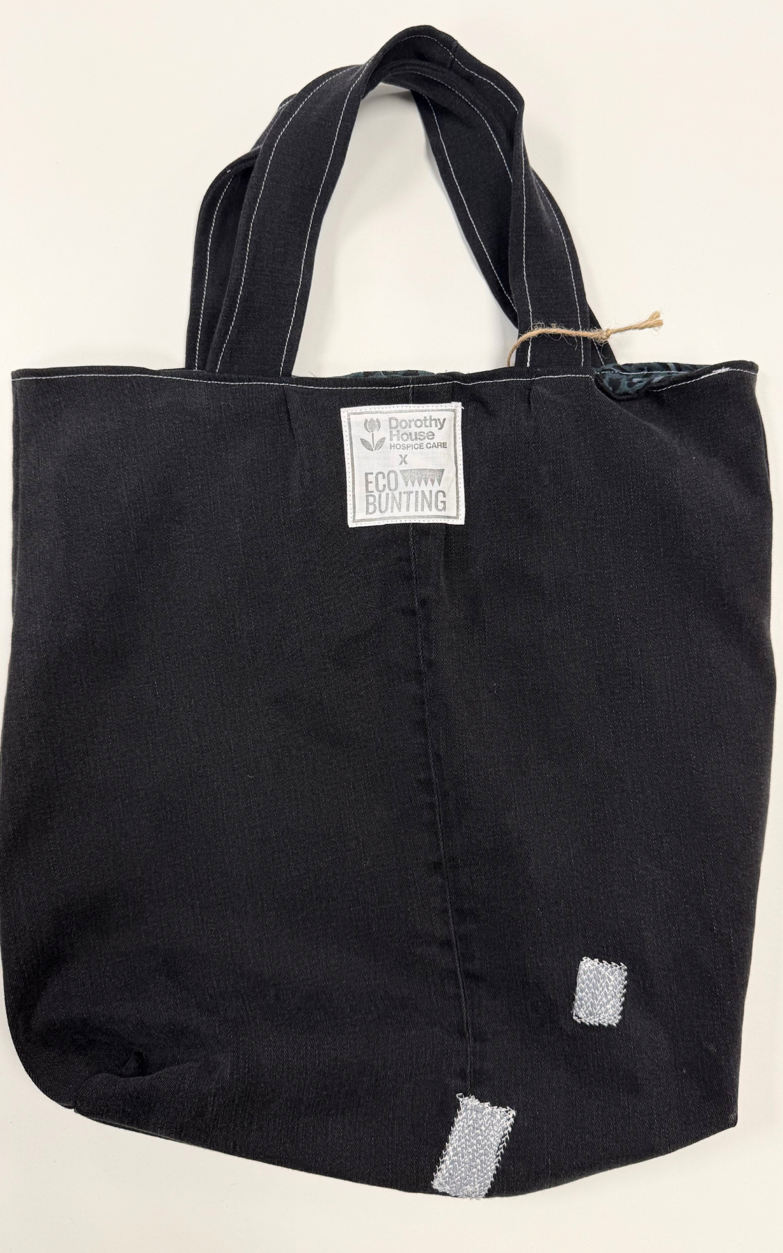 Black tote bag with a visible brand label on a beige background