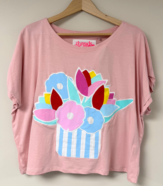 Pink t-shirt with colorful flower design on a hanger
